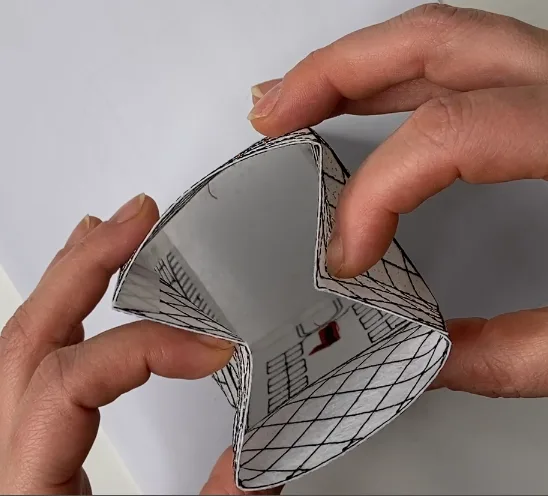 Hands folding an embroidered facade into a three-dimensional house