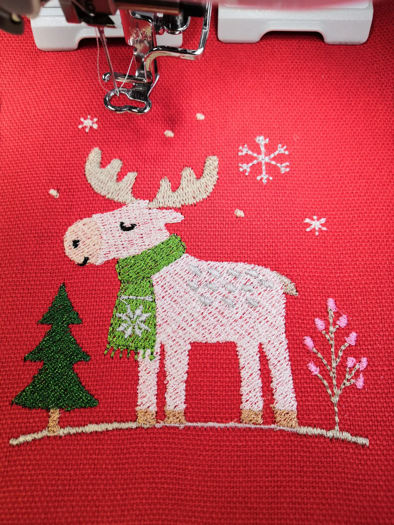 Can Stitchcraft's Winter Moose with a green scarf, Christmas tree and snowflakes, stitched onto red fabric